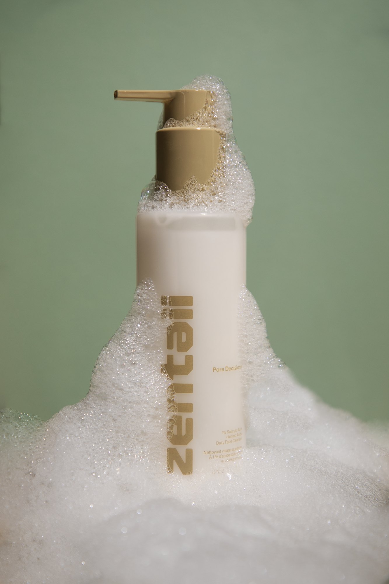 Pore Decision, the cream pump cleanser, on a sage ground with a mound of foam spilling around its base.